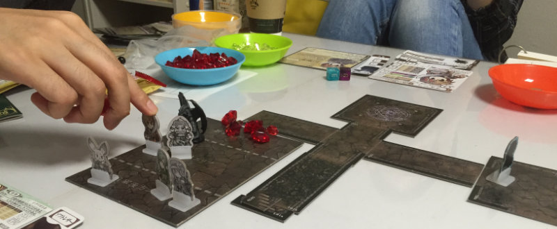 The battle map (left) and dungeon tiles (right). Three characters are in the player rear and two characters are in melee with a monster. The plastic miniature is not part of the starter set. The red health counters on the battle map are the enemy’s health.