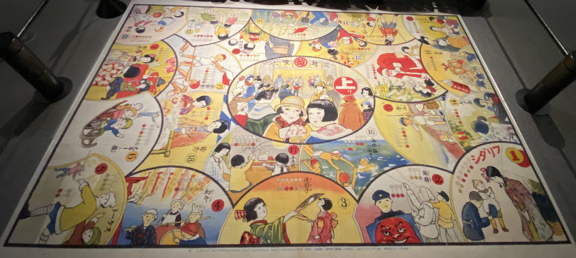 Large carpet sugoroku. Each space is a partial circle depicting a holiday. The middle is a circle showing people at Mitsukoshi.