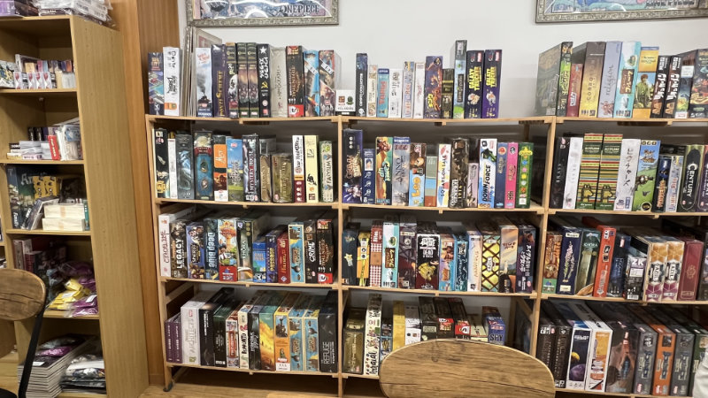 Lots of board games on wooden shelves.
