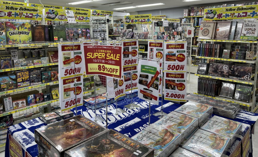 View of the shop from the entry way showing a table with sale items and shelves of games in the background.