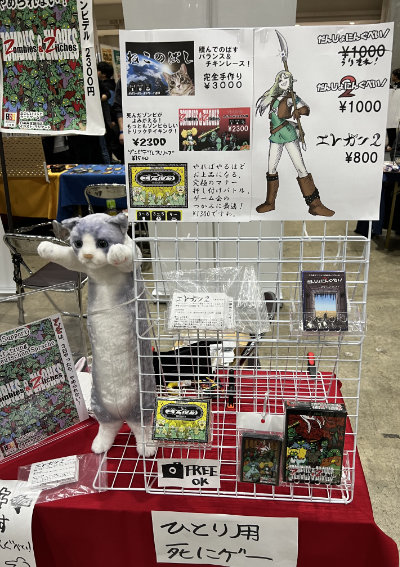 Booth display showing games and a stuffed cat standing upright.