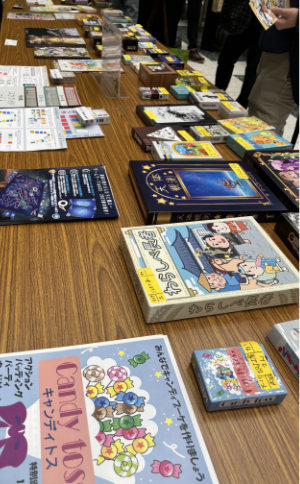 Sample games lined up on a table. Yellow tags on them indicate the associated booth.