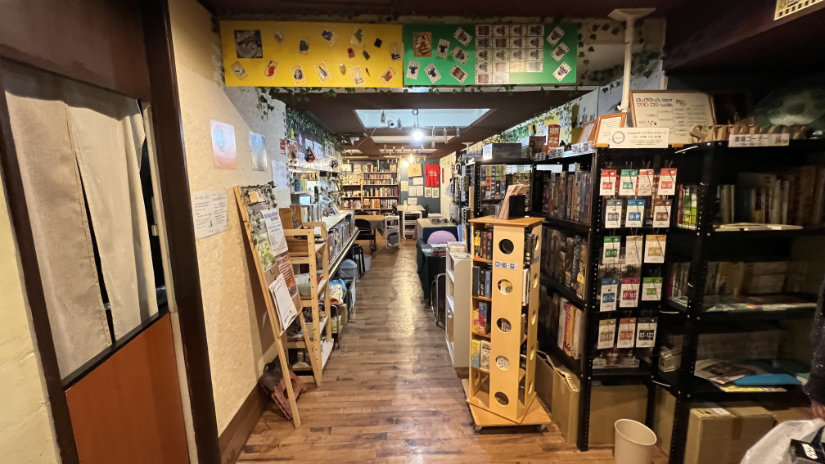 View of the shop from the entry. A narrow entry leads to space that widens with more tables and shelves of games.