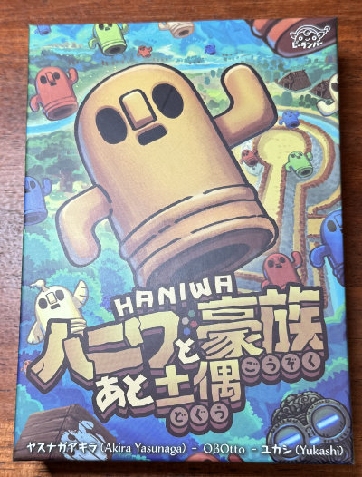 Front of the box showing a Haniwa in the foreground above a kofun, and various game elements in the background.